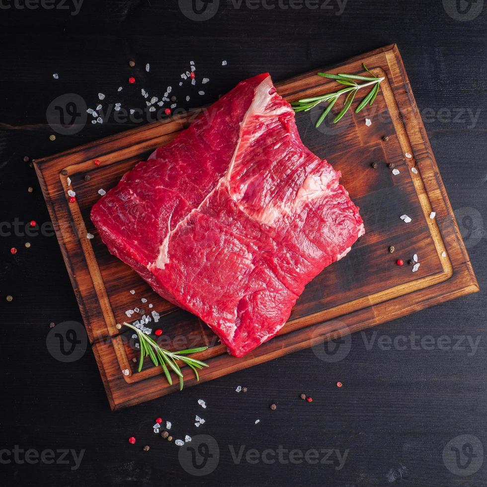 rauw vlees, biefstuk met kruiden op snijplank op donkere achtergrond met rozemarijn, foto