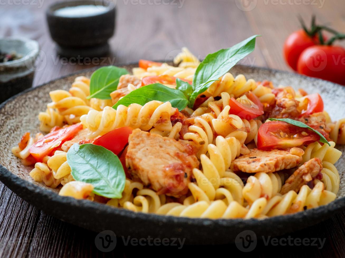 fusilli pasta met tomatensaus, kipfilet met basilicumblaadjes foto