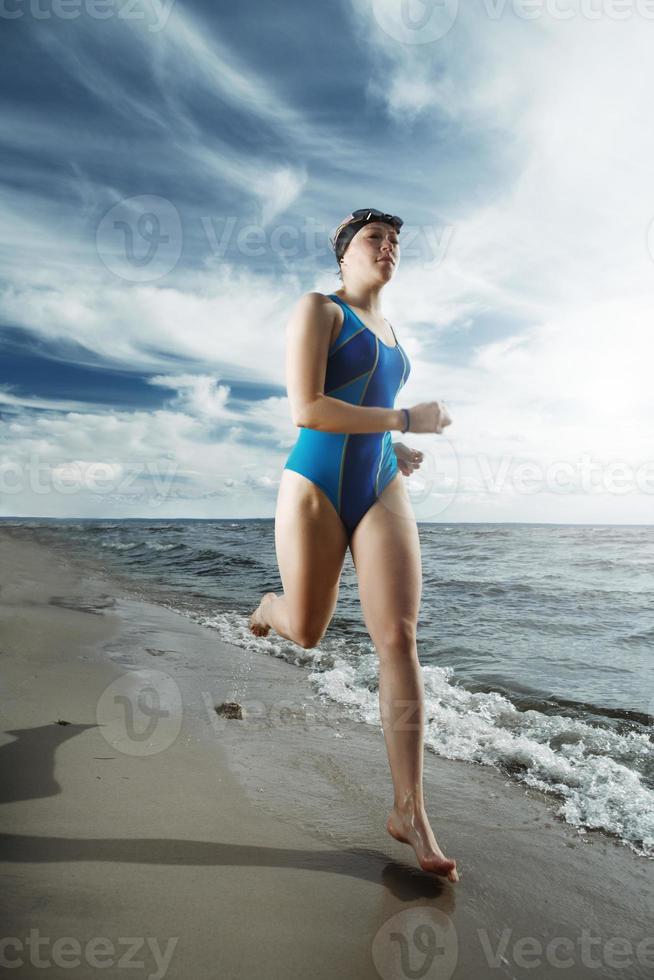 jonge vrouw atleet draait op het strand foto