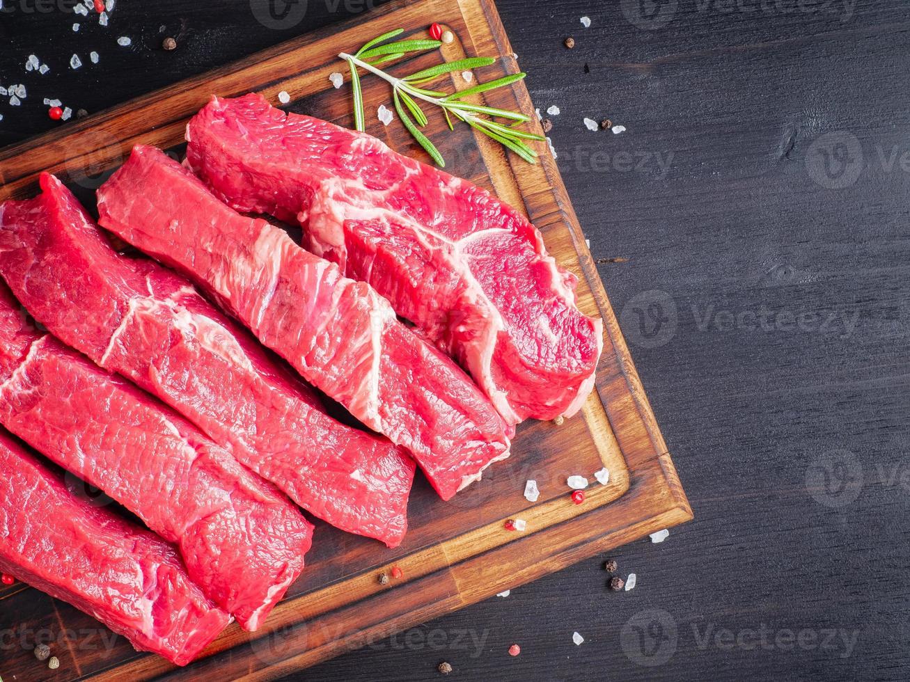 rauw vlees, biefstuk met kruiden op snijplank op donkere achtergrond met rozemarijn, foto