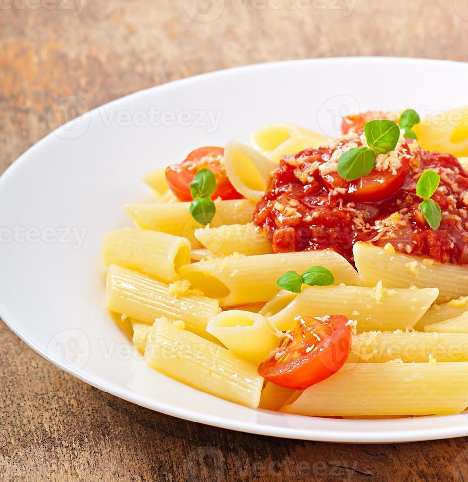 penne pasta met bolognesesaus, Parmezaanse kaas en basilicum foto