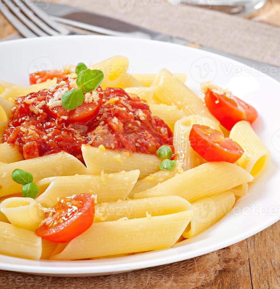 penne pasta met bolognesesaus, Parmezaanse kaas en basilicum foto