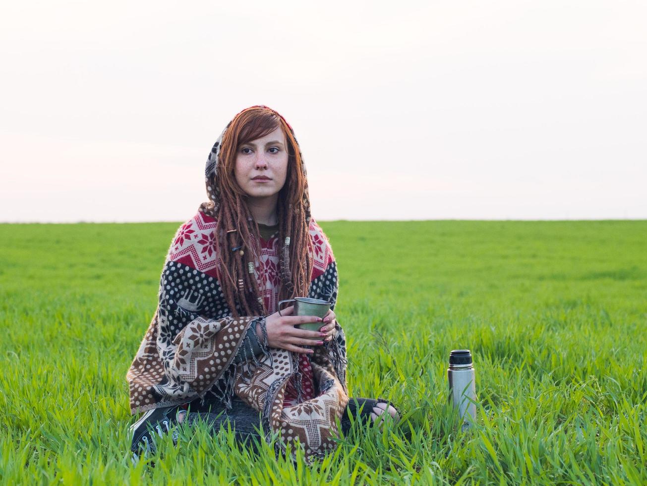 jonge vrouw drinkt thee in het veld foto