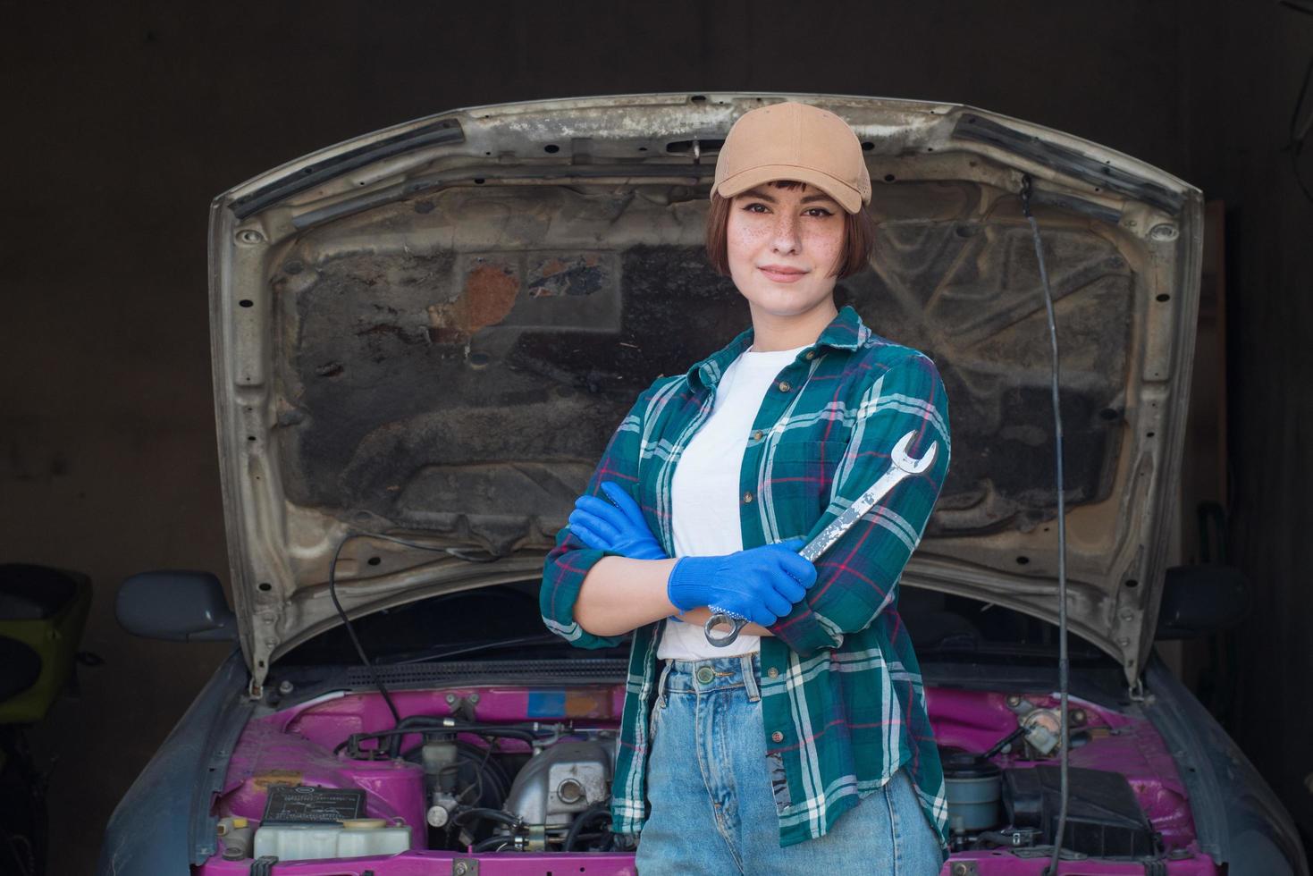 vrouwelijke monteur die auto in een garage repareert foto