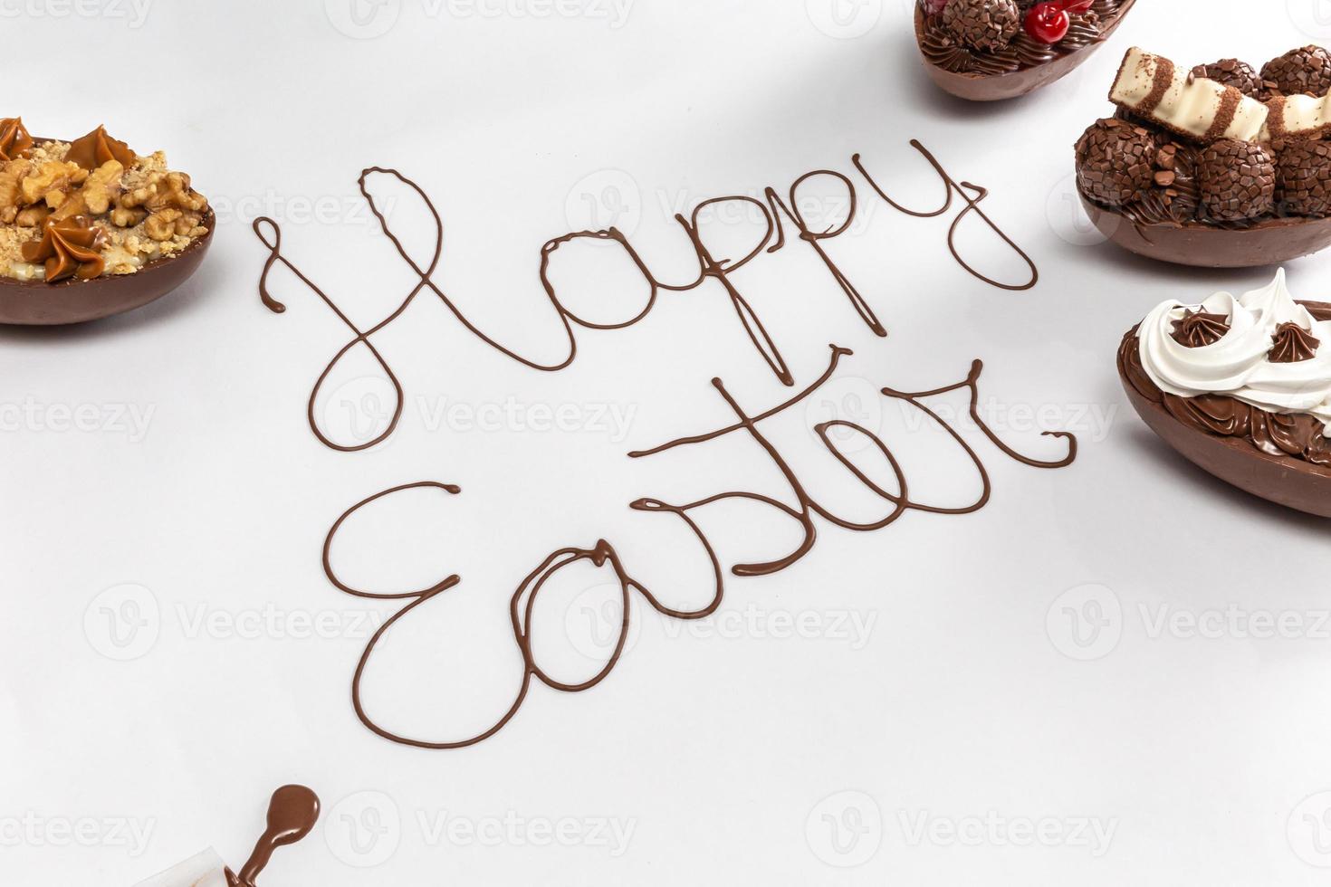 vrolijk pasen geschreven met gesmolten chocolade op witte achtergrond. met gastronomische paaseieren aan de zijkanten. foto