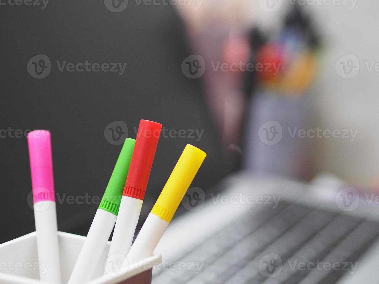 veel magische pen rode, roze, gele, groene kleur in bruine plastic doos, wazig van notebook achtergrond foto