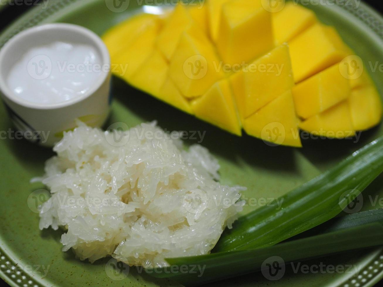 mango plakkerige rijst met kokosmelk, zoet voedseldessert op groene plaat, barracuda mango geel fruit foto