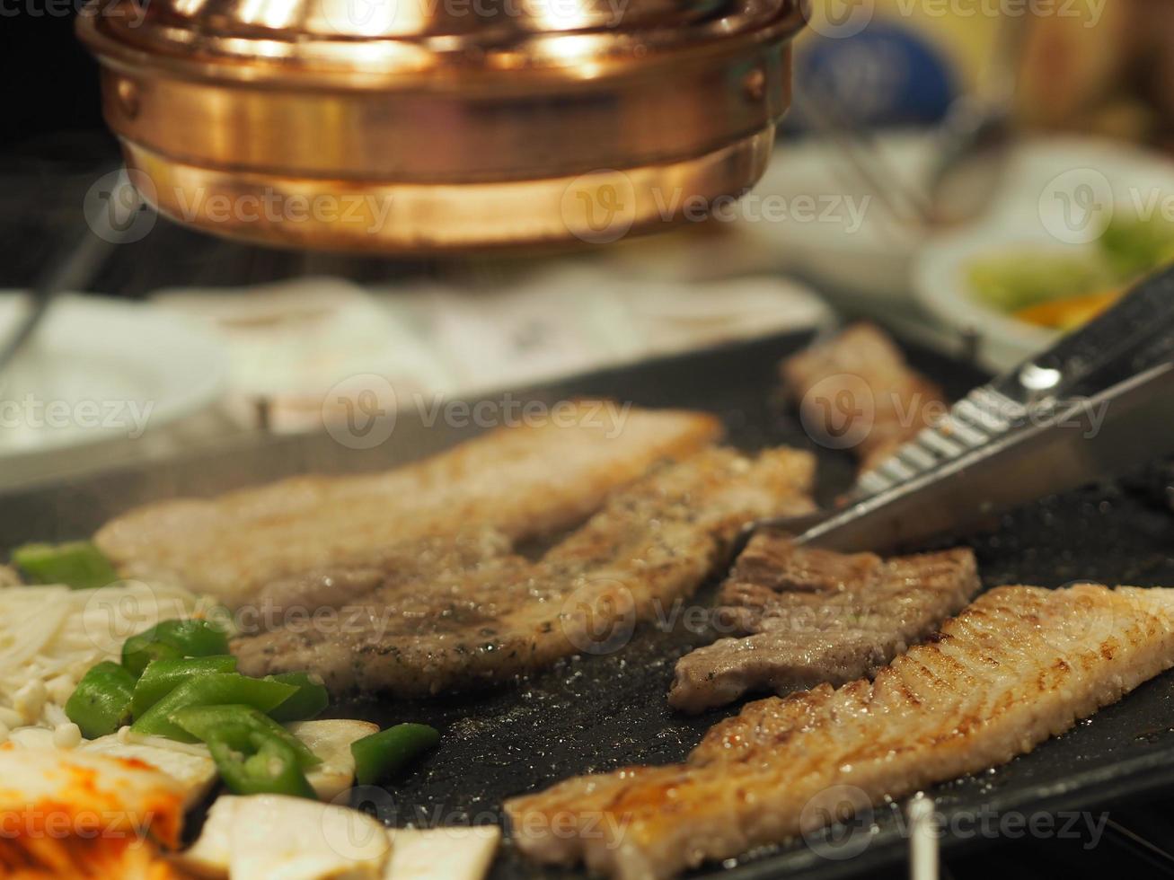 gegrild varkensvlees is op de pan in thaise stijl, thais buffet met varkensvlees, kip en ander vlees, gekookt op koperen barbecuepan, varkensgrill, bar-bq, thaise barbecue, koreaanse barbecue yakiniku eten varkensvlees foto