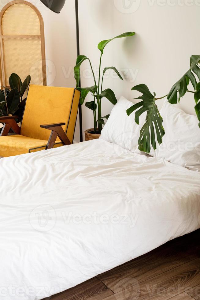 kamerinterieur met comfortabele gele stoel, bed en plant in de buurt van witte muur foto