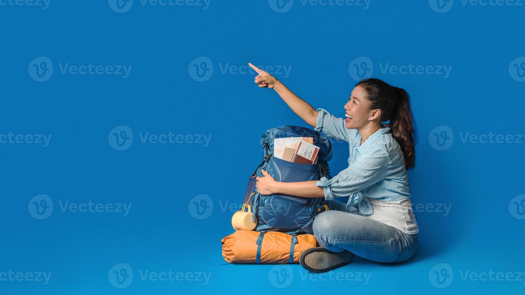 jonge Aziatische reiziger gelukkige vrouw in blauw shirt met rugzak met en uitrusting voor reizigers vakantie met een kaart, op blauwe kleur achtergrond. reis rugzak foto