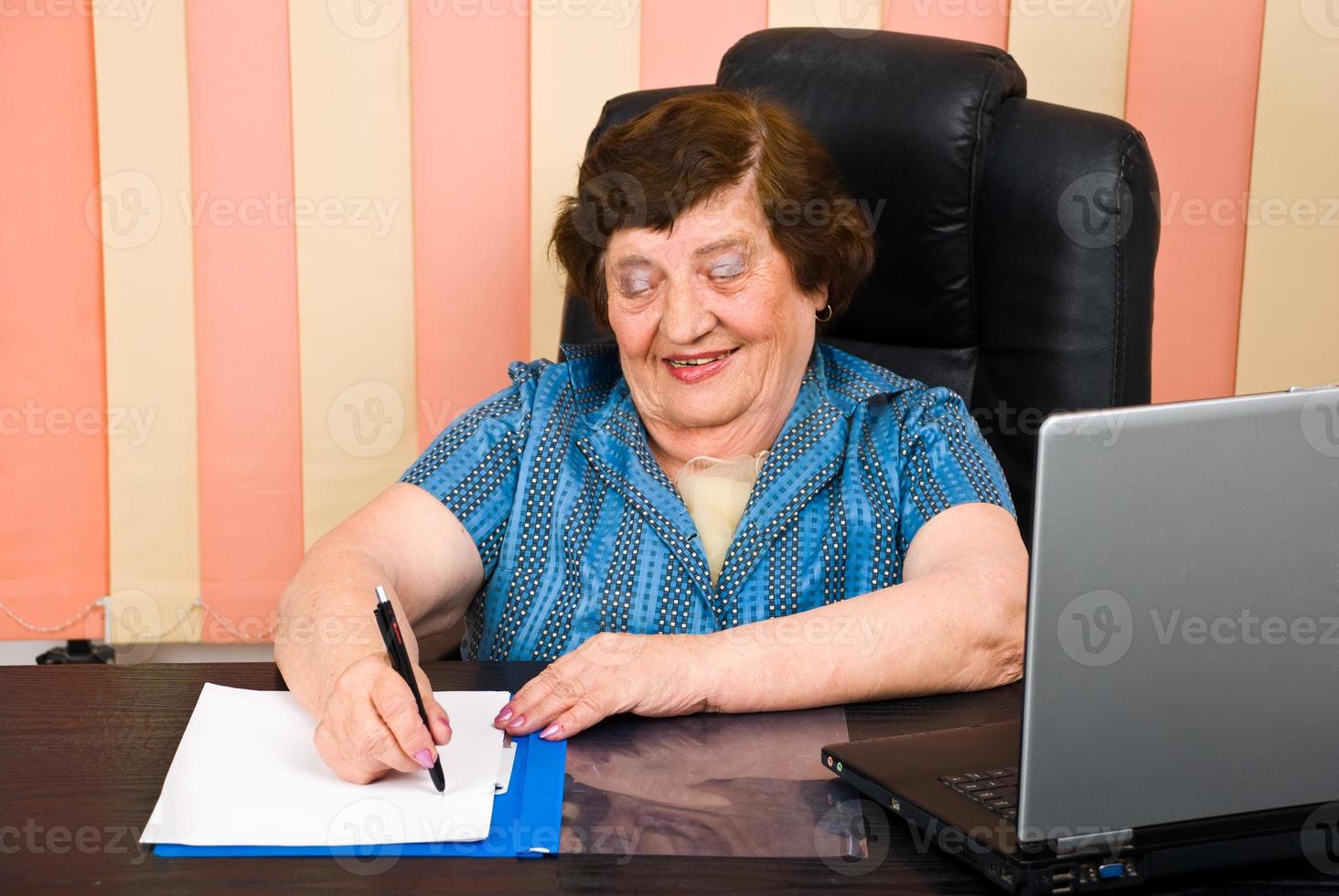 lachende oudere vrouw schrijft op papier foto
