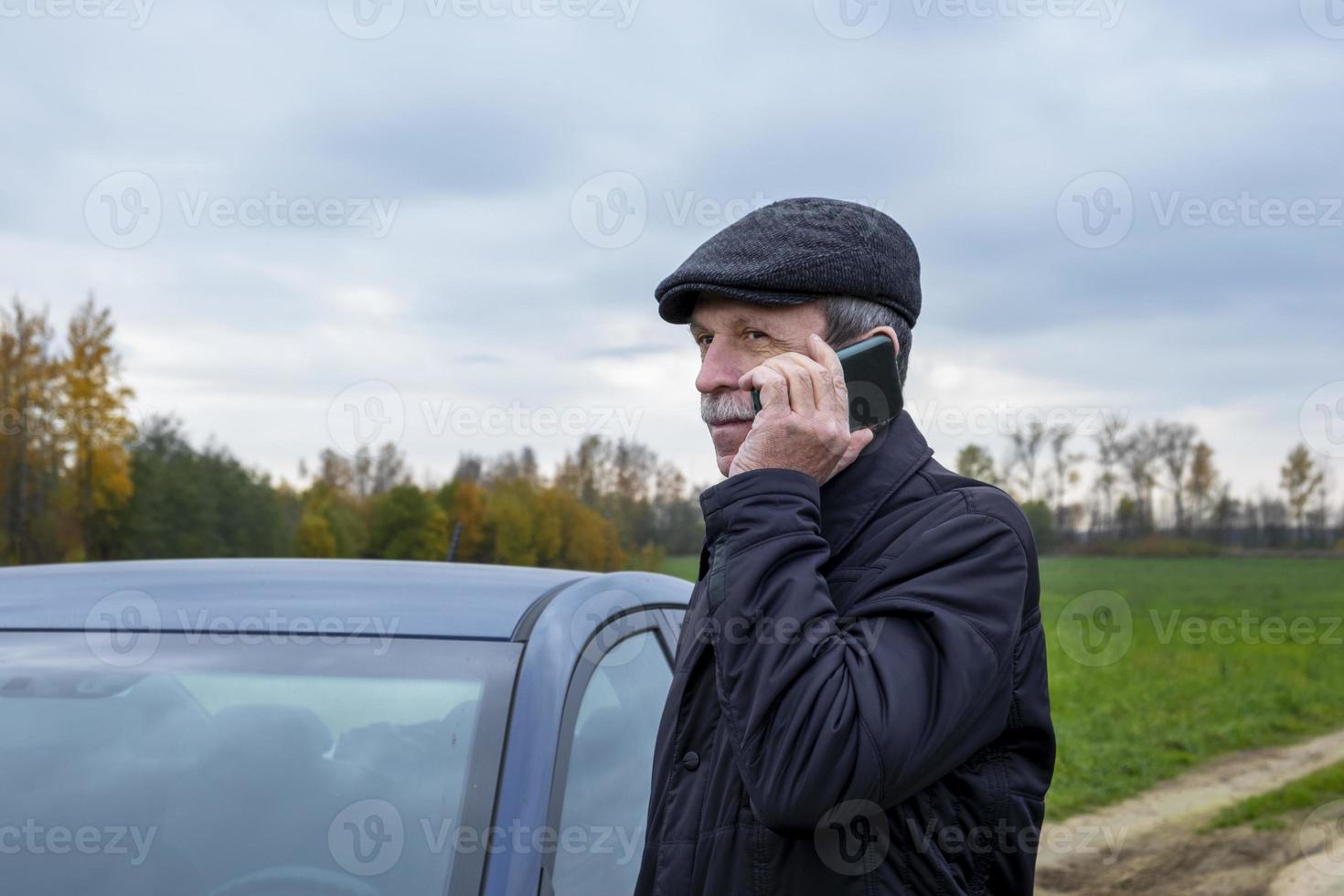 gepensioneerde stapt in auto en praat op smartphone foto