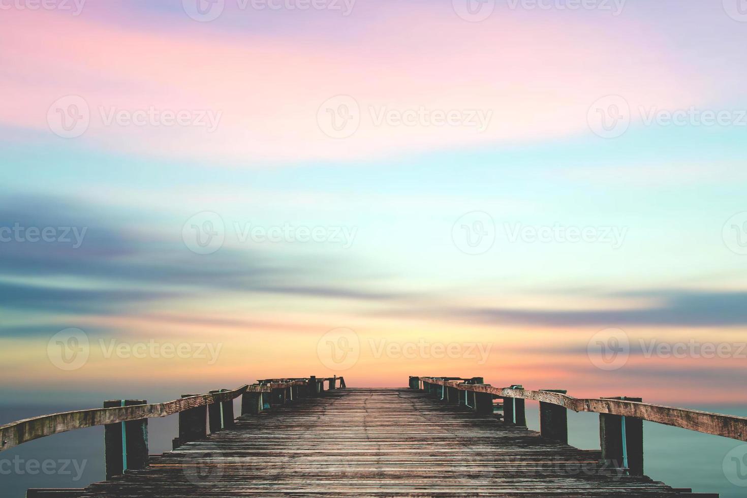 een houten brug die uitsteekt in de zee met een prachtig uitzicht. foto