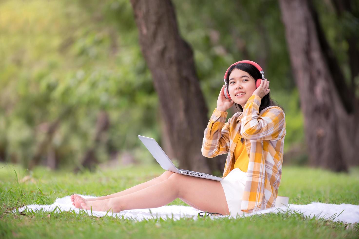 een mooie Aziatische vrouw ontspant in de tuin, leest en zoekt leerinformatie van internet foto