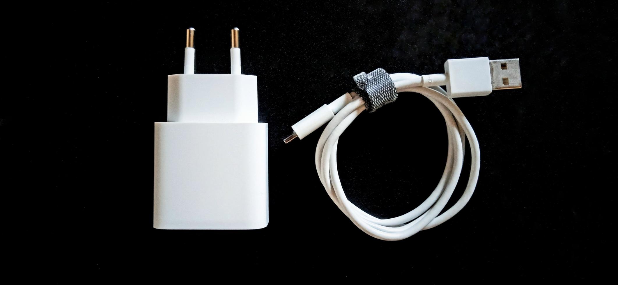 witte smartphone-oplader op de zwarte achtergrond. smartphone opladen elektronisch apparaat. foto