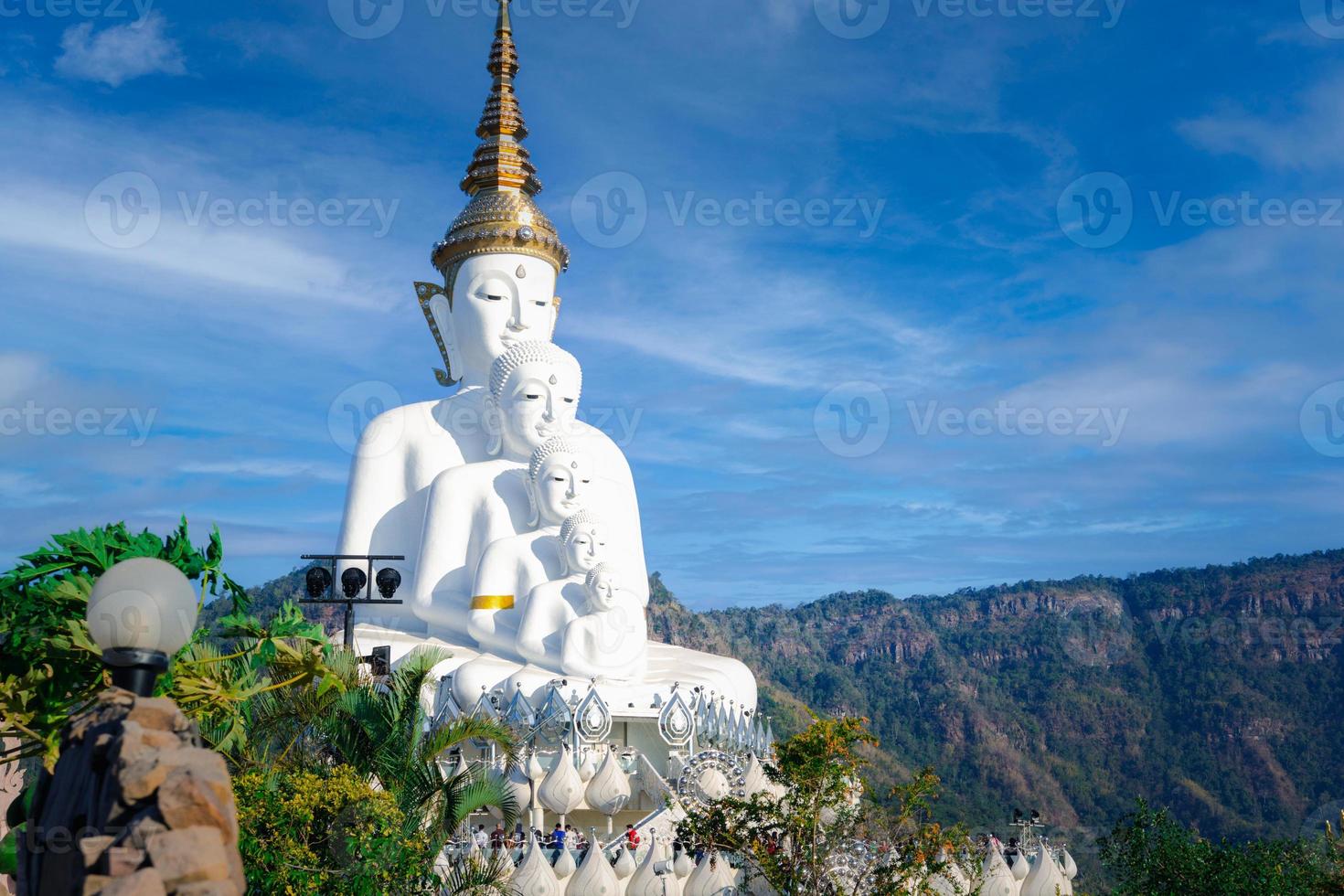 weids uitzicht een groot wit boeddhabeeld achter een berg en een blauwe lucht in wat pha son kaew, khao kho district, phetchabun provincie, thailand foto