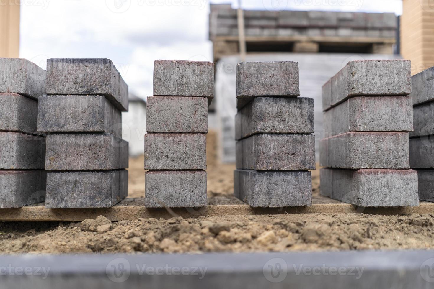 leggen van grijze betonnen bestrating platen in het huis binnenplaats oprit patio. professioneel werkende metselaars plaatsen nieuwe tegels of platen voor de oprit, stoep of terras op een vlakke zandondergrond. foto