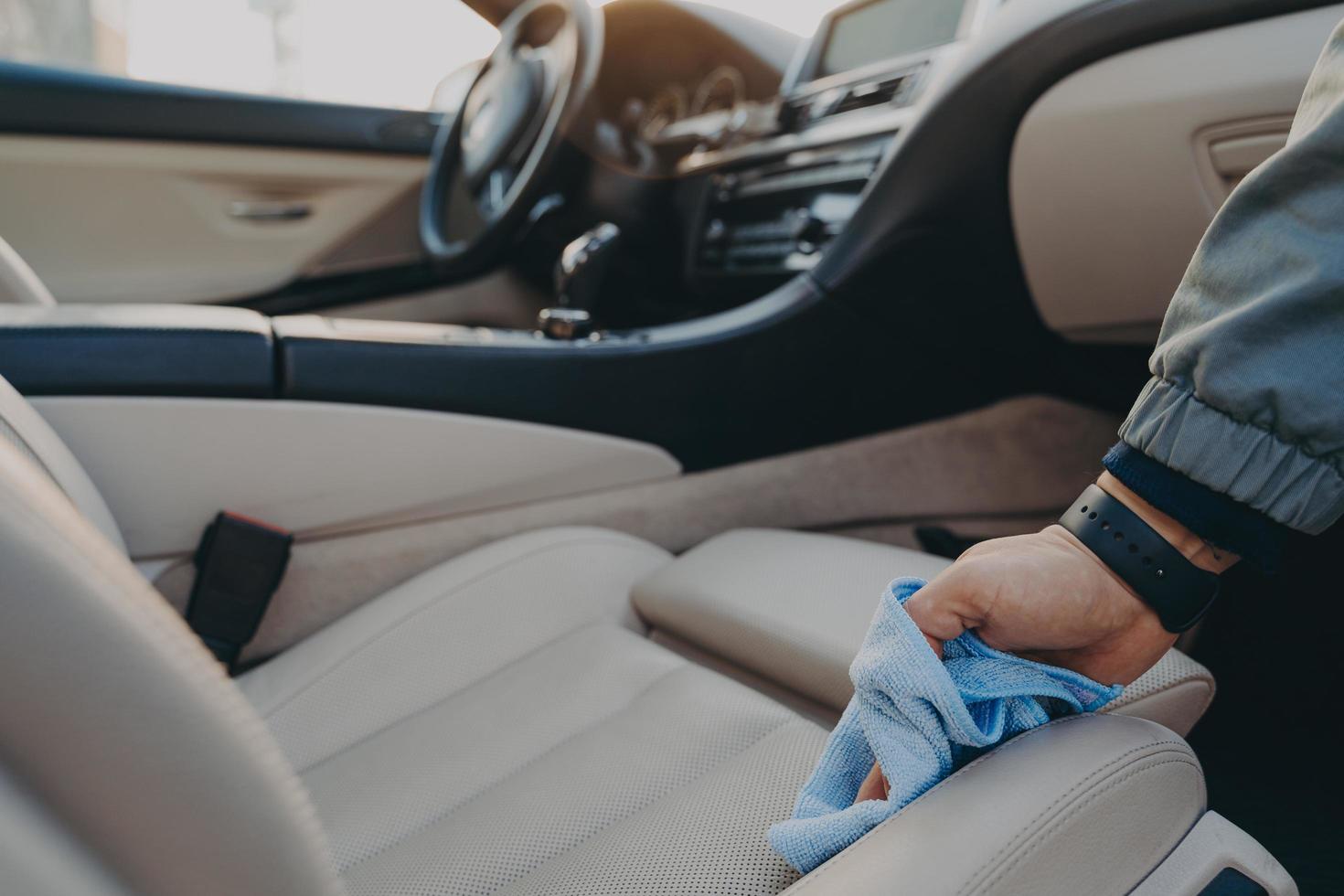 man die auto-interieur schoonmaakt met microvezeldoek bij carwashservice foto