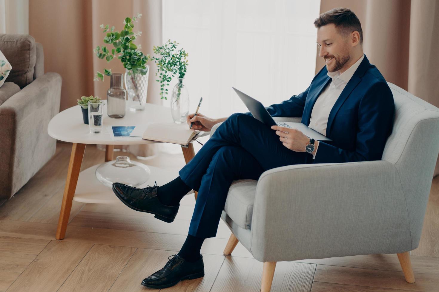 gelukkige jonge zakenman die geniet van thuiswerken in de woonkamer foto