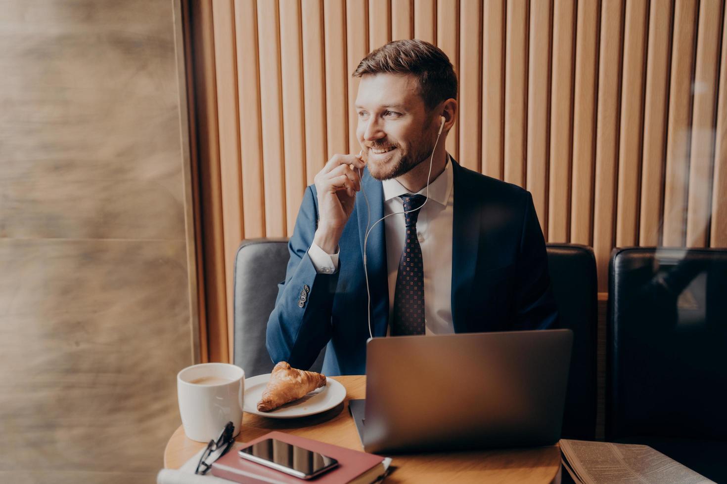 mannelijke investeerder in blauw pak in gesprek met zakenpartner online via laptop in restaurant foto