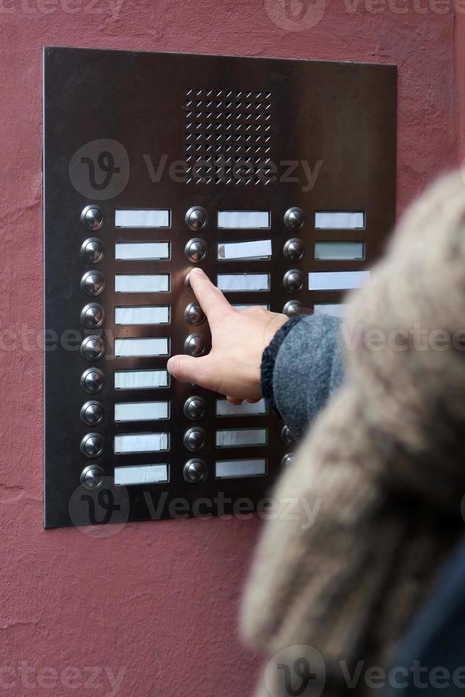 vinger op de deurbel drukken bij flatgebouw foto