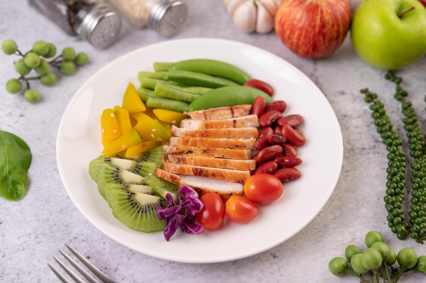 kippenbiefstuk met erwten, tomaten, kiwi en pompoen. foto