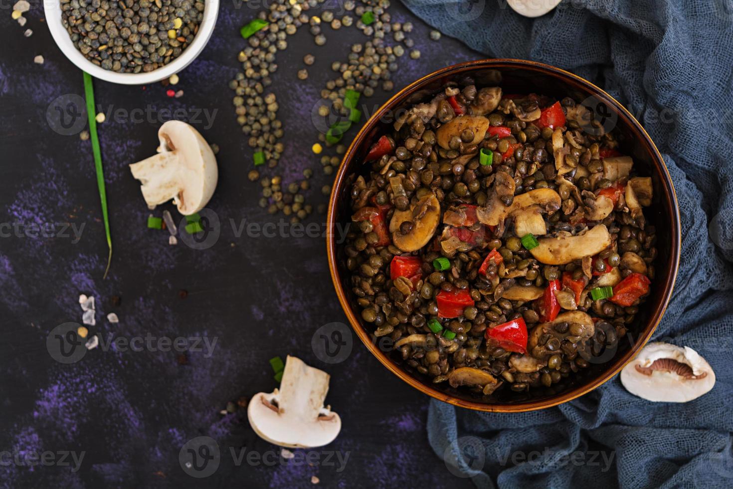 heerlijke linzen met peper en champignons op donkere achtergrond foto