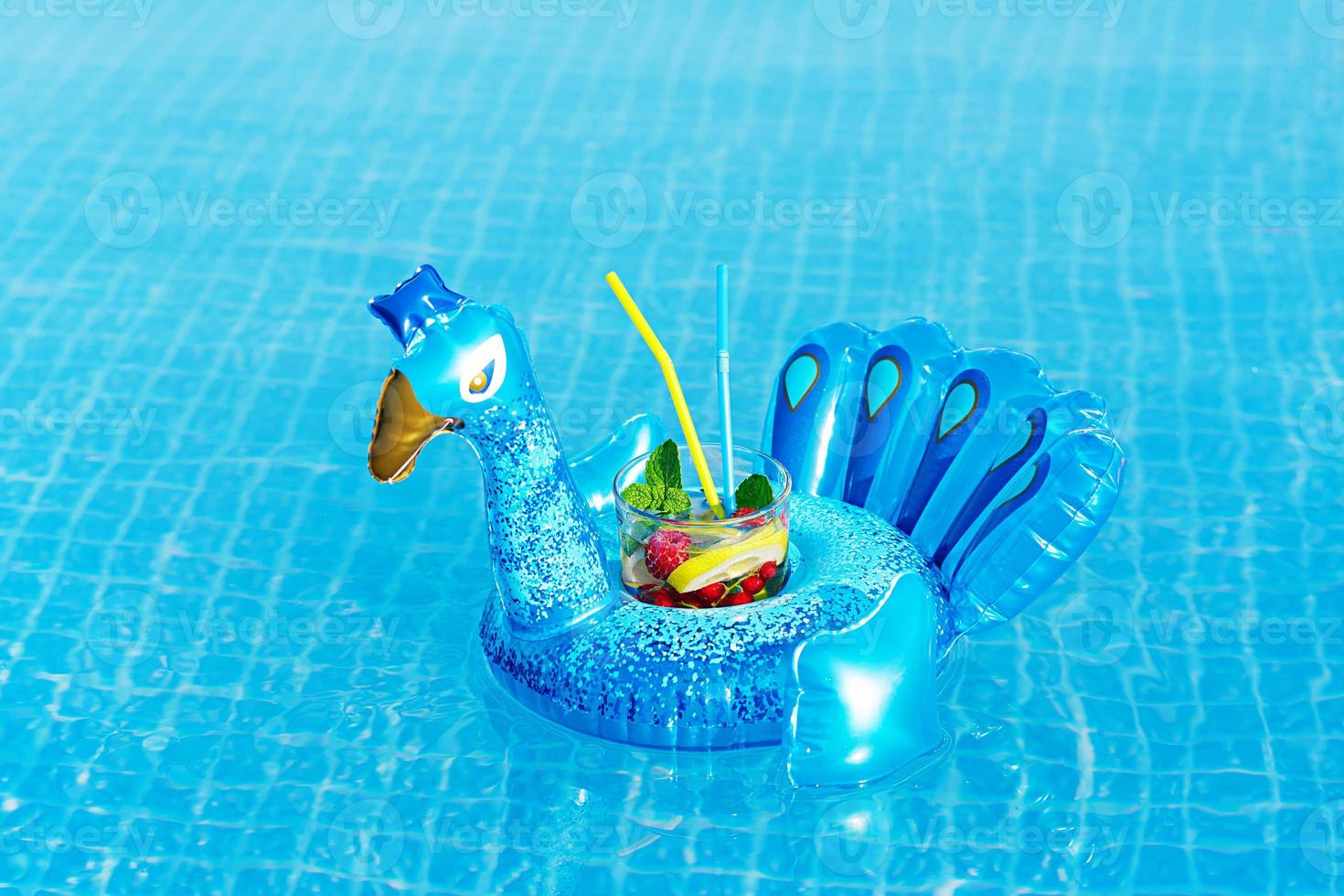 verse cocktailmojito op opblaasbaar blauw pauwstuk speelgoed bij zwembad. vakantie concept. foto