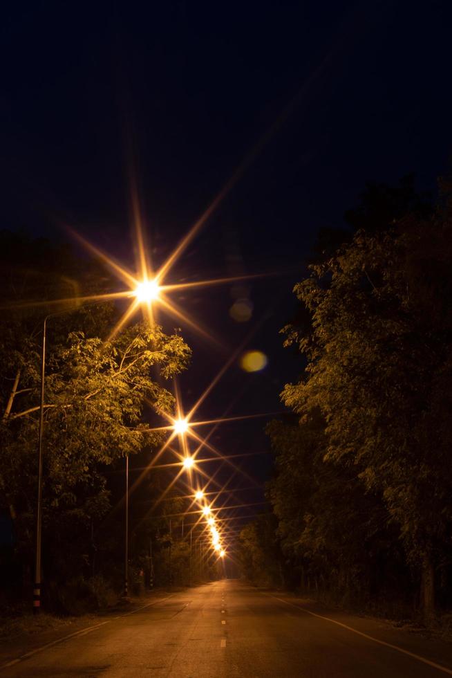 verlicht veel lampen met bomen op schemerstraat. foto