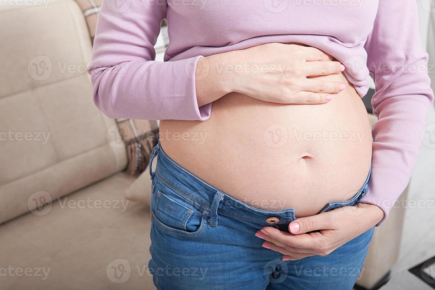 afbeelding van zwangere vrouw die haar buik thuis met handen aanraakt. kopieer ruimte en bespotten. bijgesneden afbeelding foto