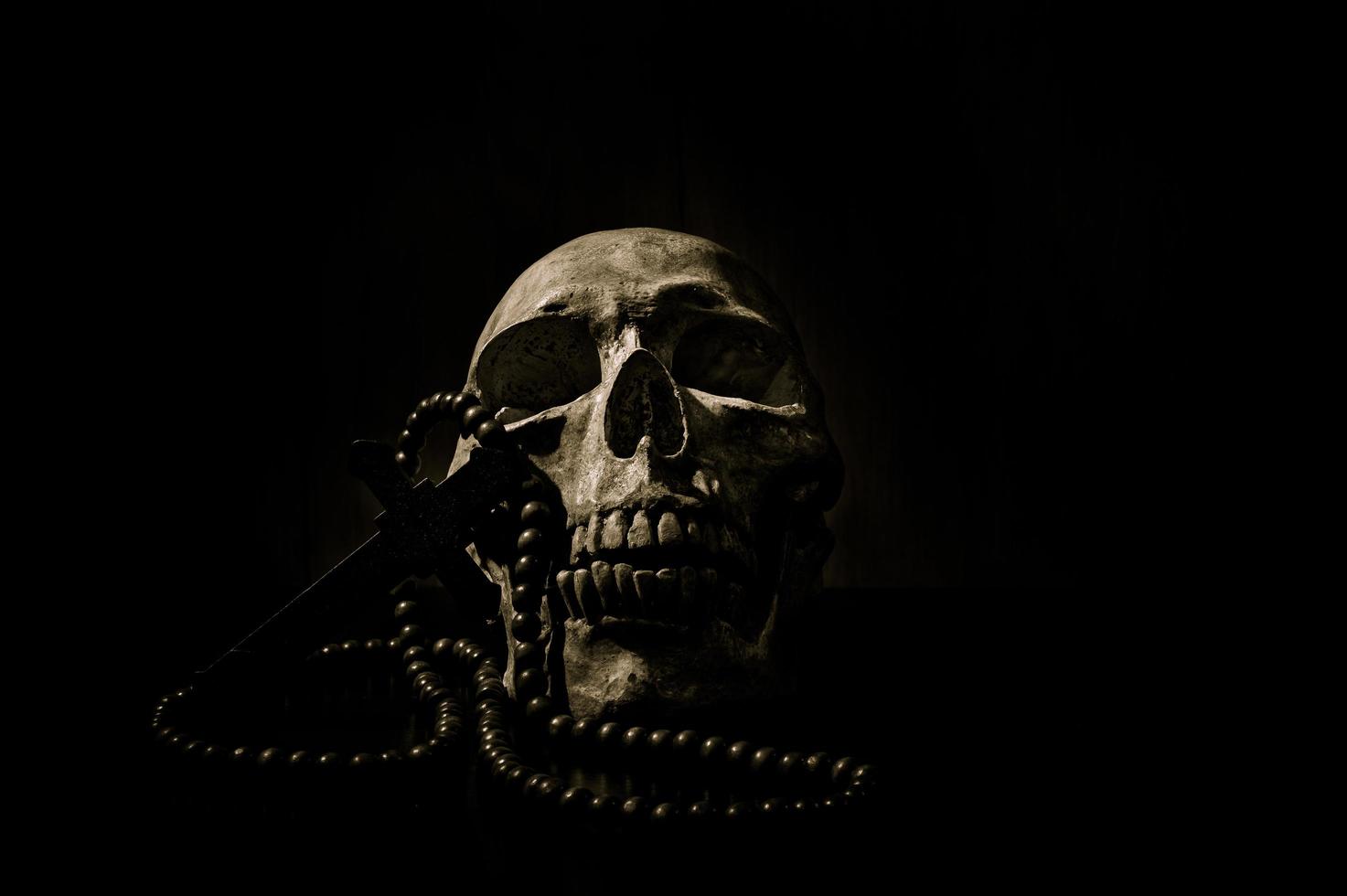 stillevenkunst van een menselijke schedel en kraal op een zwarte achtergrond foto