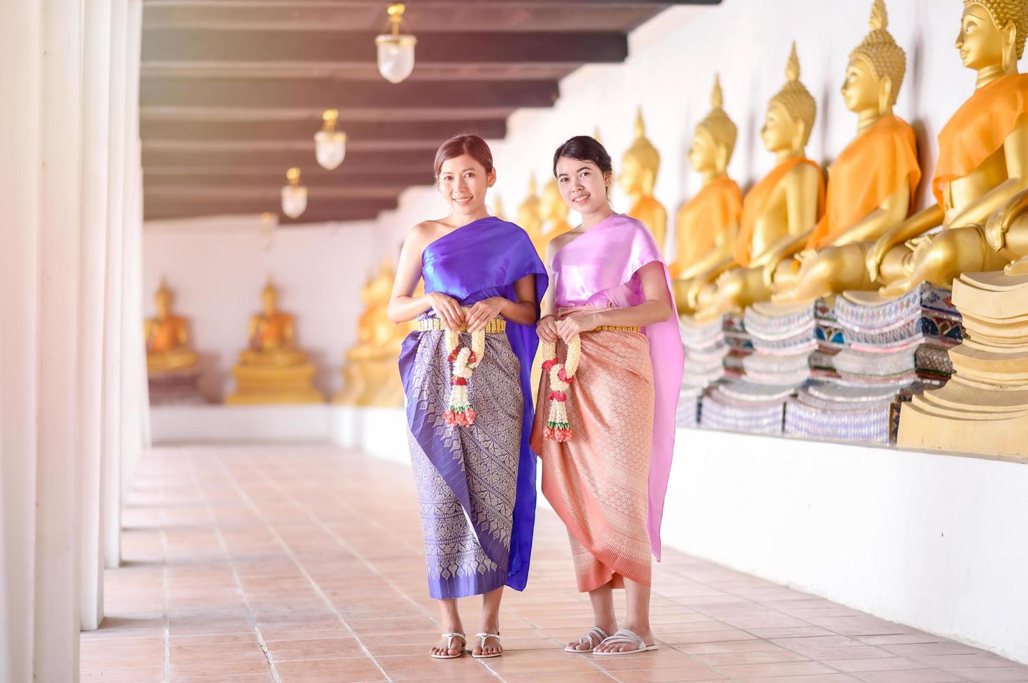 aantrekkelijke thaise vrouwen in traditionele thaise kleding houden verse bloemenslingers voor het betreden van een tempel op basis van de songkran-festivaltraditie in thailand foto