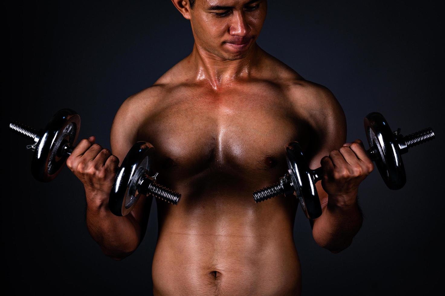 de sterke Aziatische man tilde zijn halter regelmatig op om zijn spieren sterk en mooi te houden foto