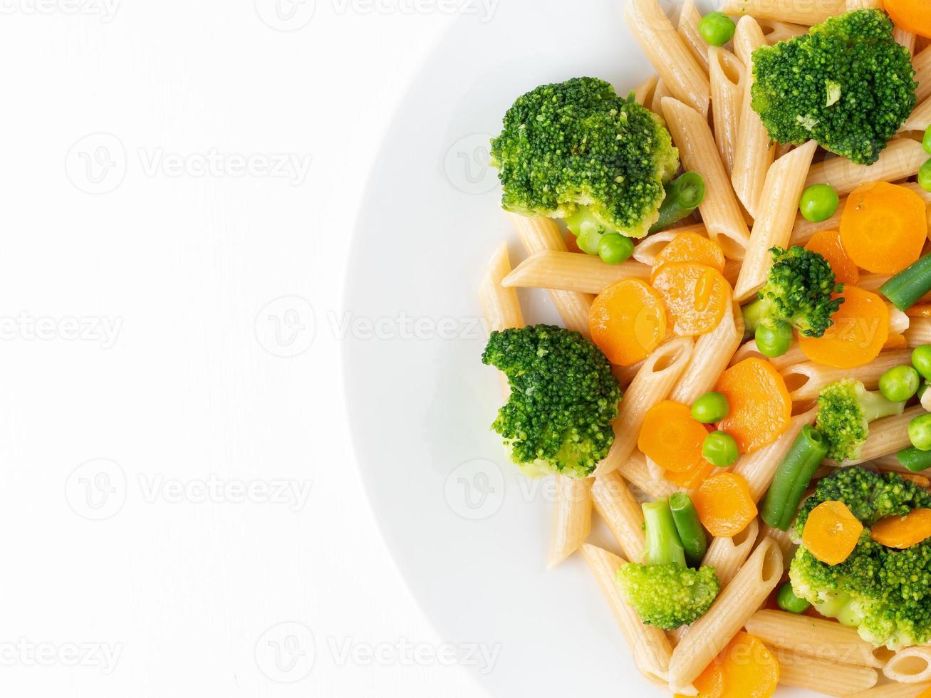 volkoren pasta penne met broccoli, wortelen, doperwtjes. deel van plaat, kopieer ruimte. dieetmenu, goede voeding, gezond eten foto