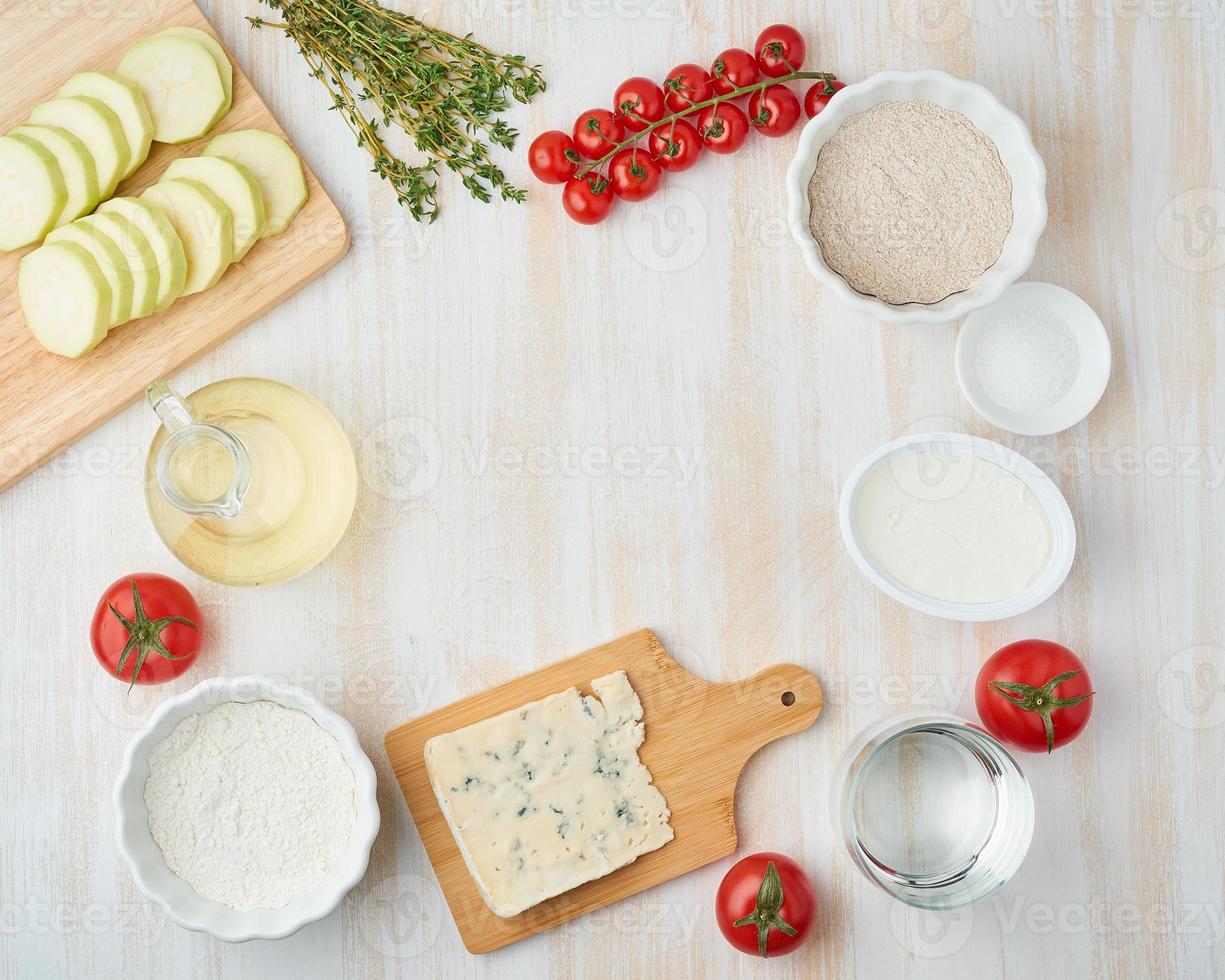 stap voor stap recept. zelfgemaakte galette met groente. bovenaanzicht, witte houten tafel foto