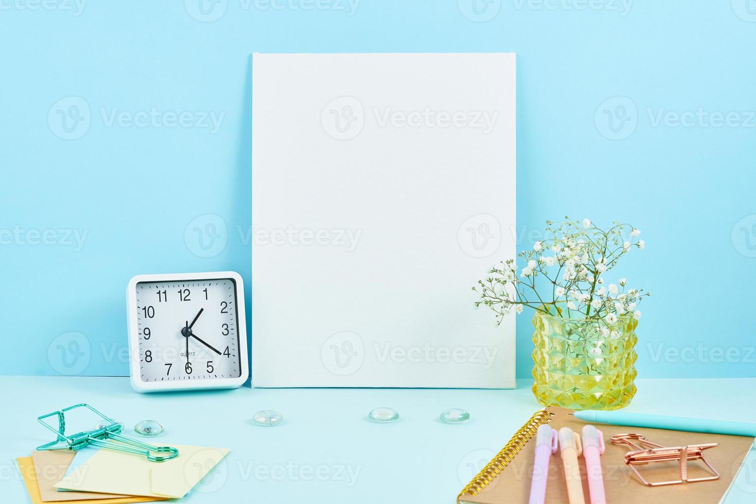 mockup met leeg wit frame op blauwe tafel tegen blauwe muur, alarm, bloem in vaze. foto