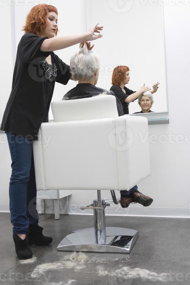 vrouwelijke kapper kapsel geven aan senior vrouw foto