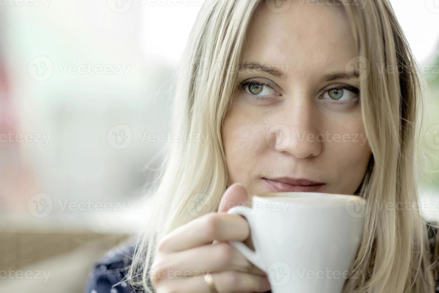 blonde vrouw koffie drinken in café foto