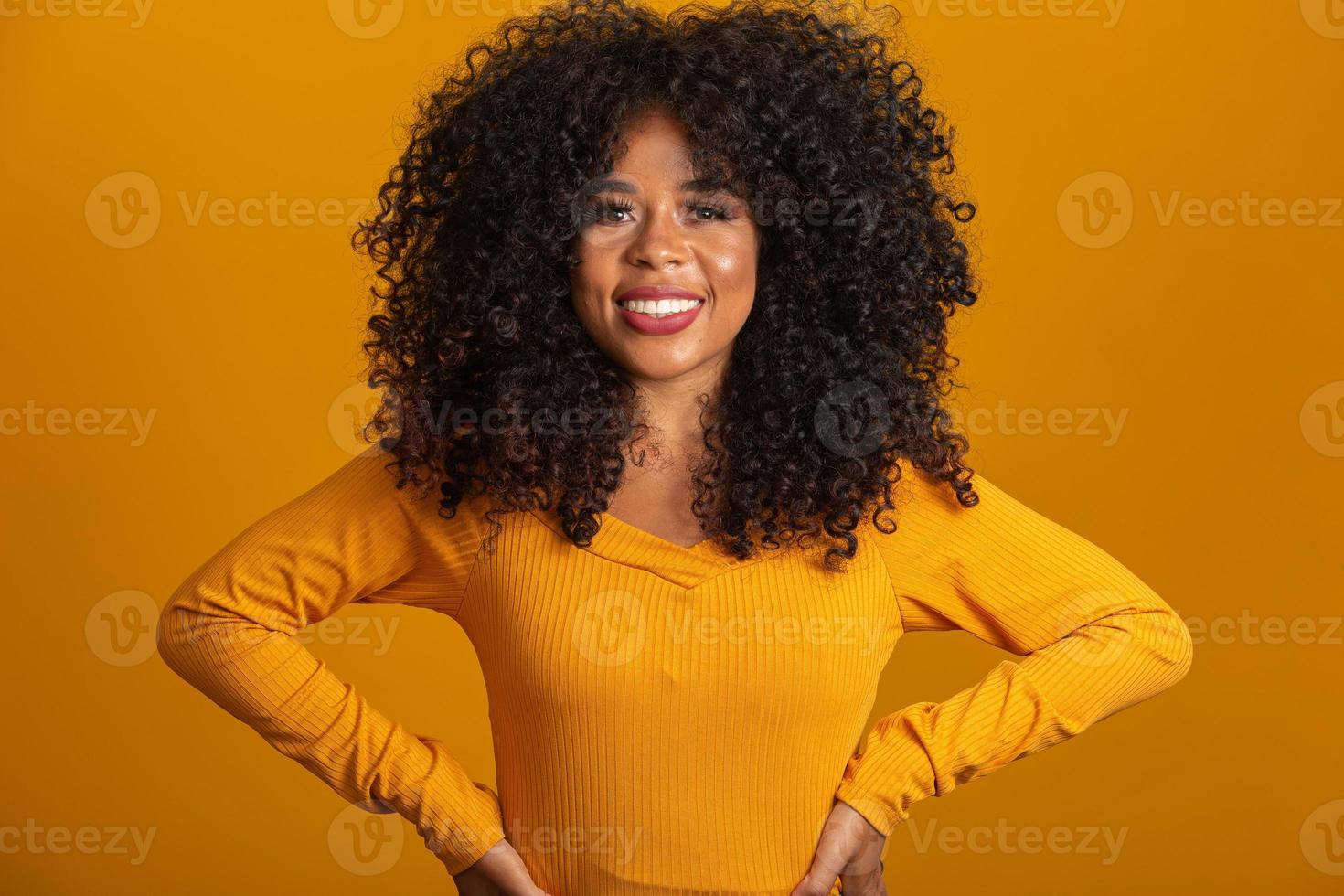 jonge Afro-Amerikaanse vrouw met krullend haar camera kijken en glimlachen. schattig afro meisje met krullend haar glimlachend camera kijken. foto