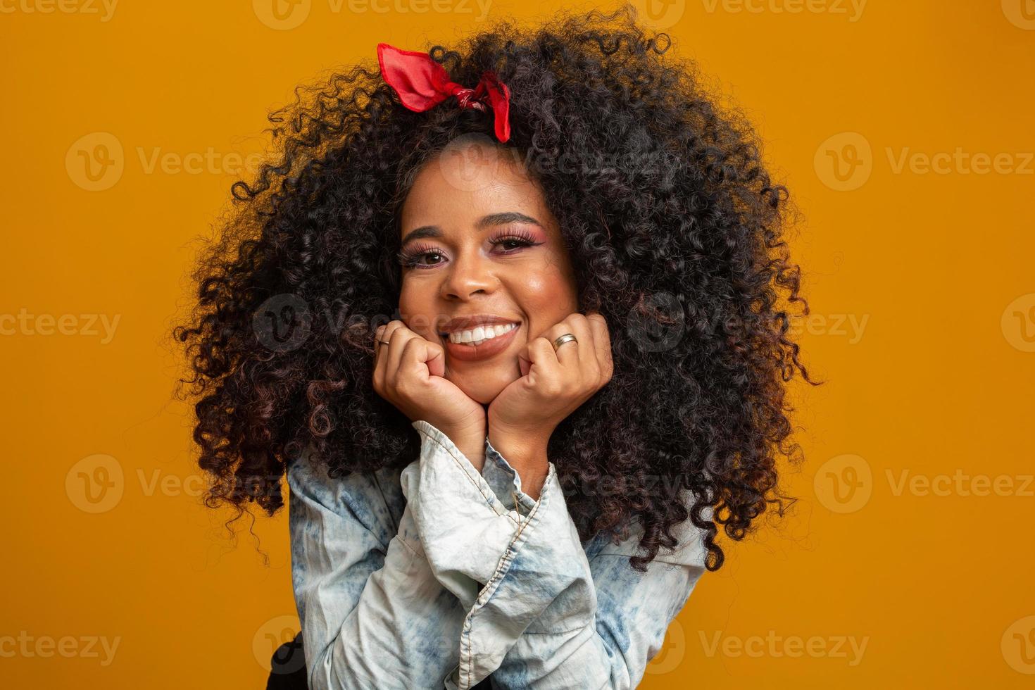 schoonheidsportret van afrikaanse amerikaanse vrouw met afrokapsel en glamourmake-up. Braziliaanse vrouw. gemengd ras. gekruld haar. kapsel. gele achtergrond. foto