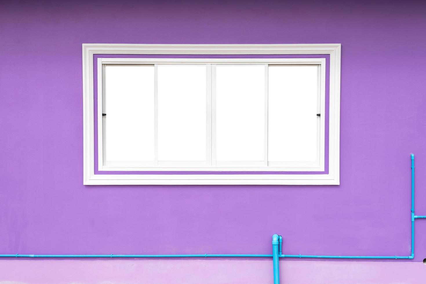 de achtergrond van het witte betonnen raamkozijn, die tegen een paarse muur en blauwe pvc-waterleidingen eronder schuift, is een veel voorkomend gezicht in de moderne hedendaagse woningbouw. foto