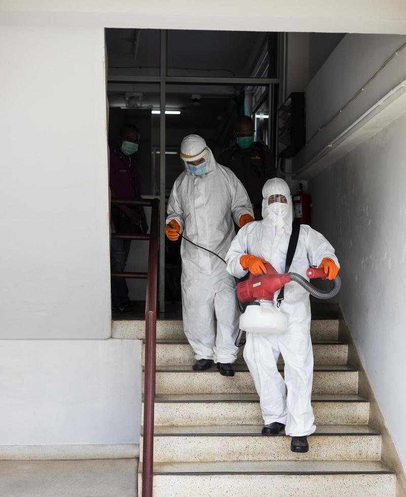 beide mannen, gekleed in pbm-uniformen, sproeiden de trappen schoon. foto