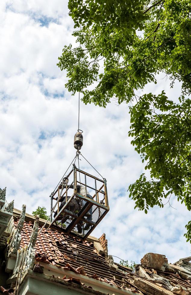 laag zicht op arbeiders in stalen manden boven de sloop van het dak. foto