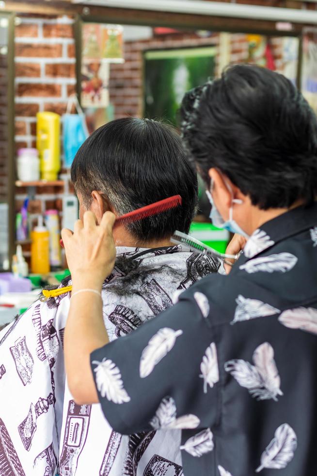 de kapper doet kappers voor een oudere Thaise man. foto