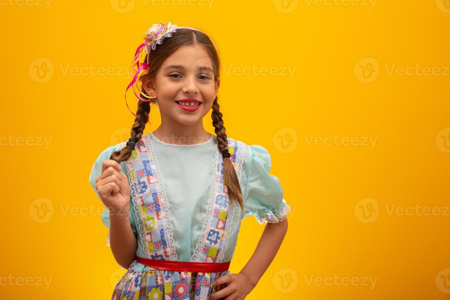 kind in typische kleding van het beroemde braziliaanse feest genaamd festa junina ter viering van sao joao. mooi meisje op gele achtergrond. foto