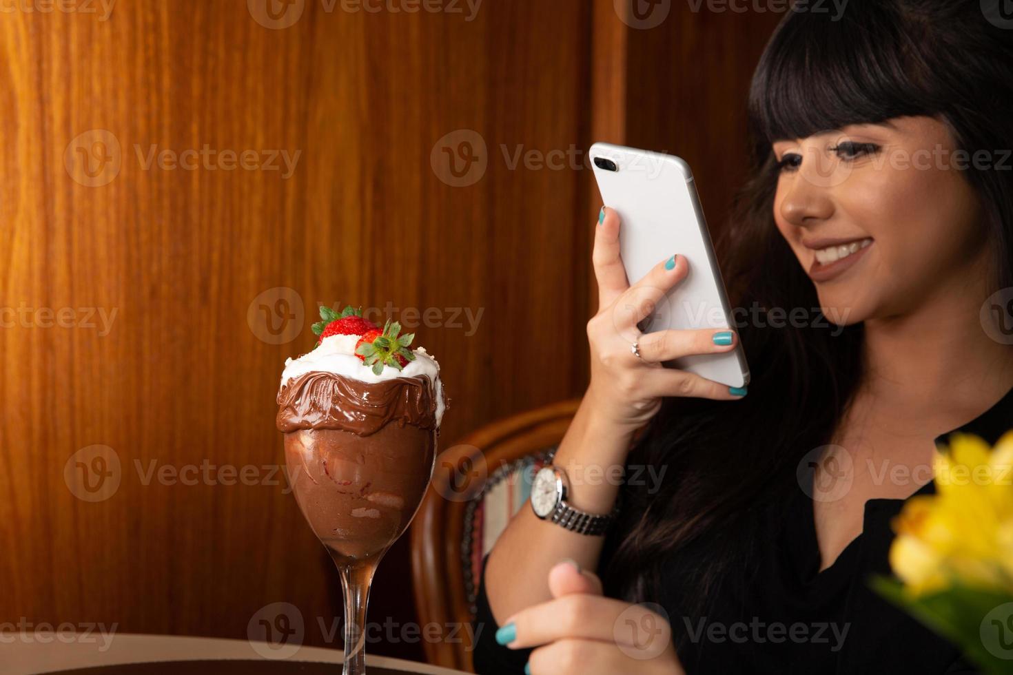 vrouw die foto's maakt van heerlijk ijs, wit combineert aardbei met een smartphone. foto