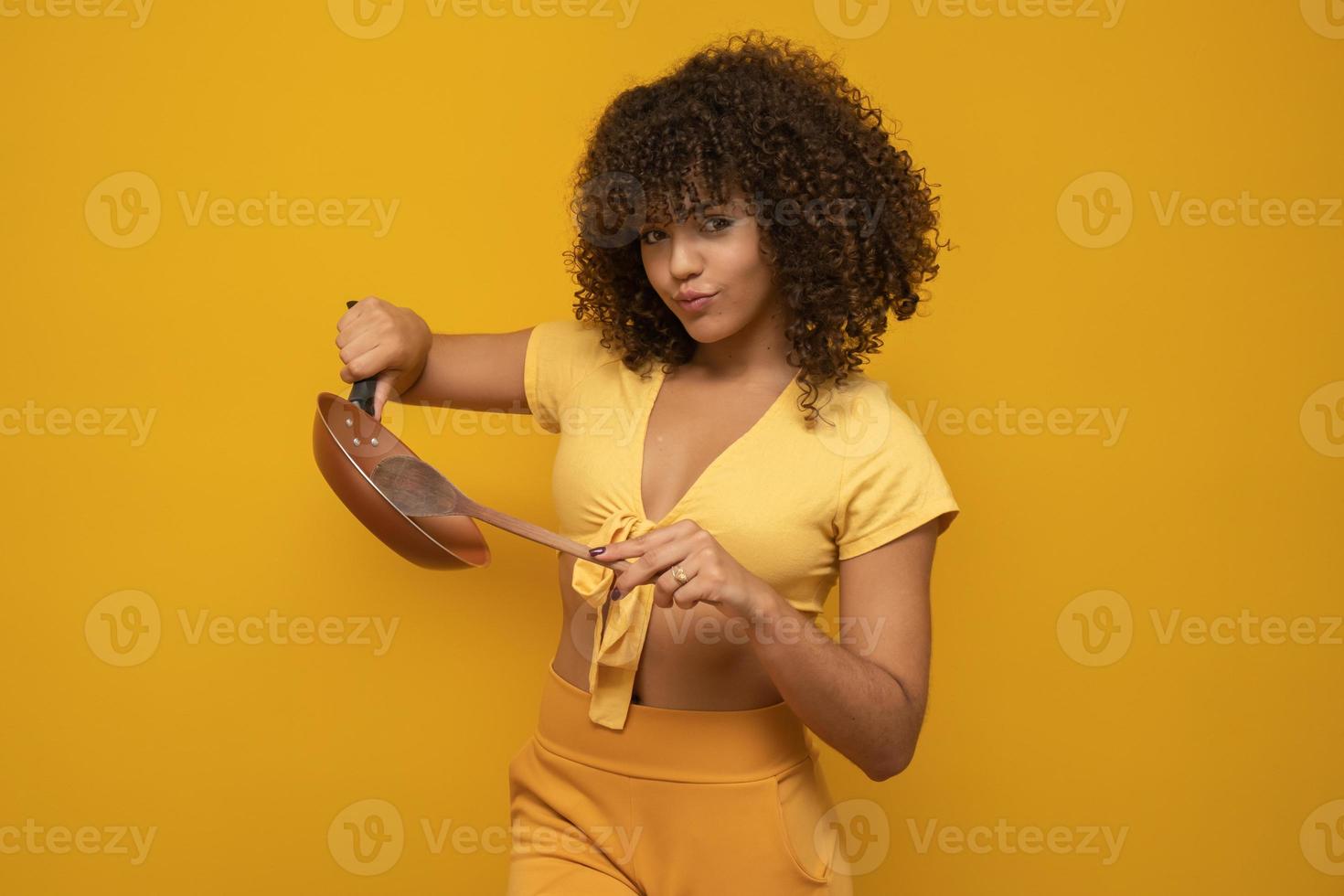 kookgerei. kokende vrouw in keuken met pan en houten lepel. huisvrouw dansen. foto