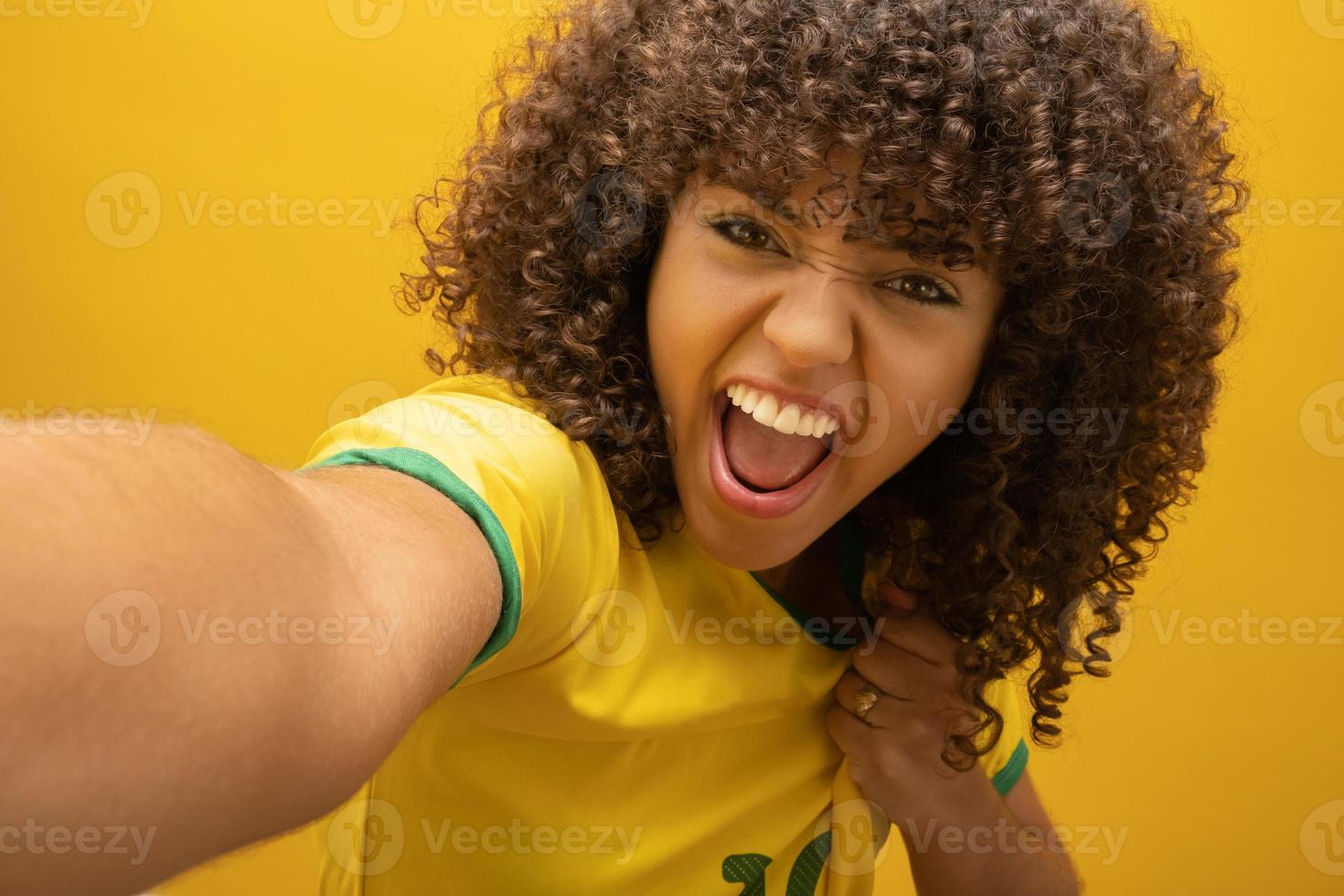 brazilie aanhanger. braziliaanse vrouw fan vieren op voetbal voetbalwedstrijd op gele achtergrond. braziliaanse kleuren. foto