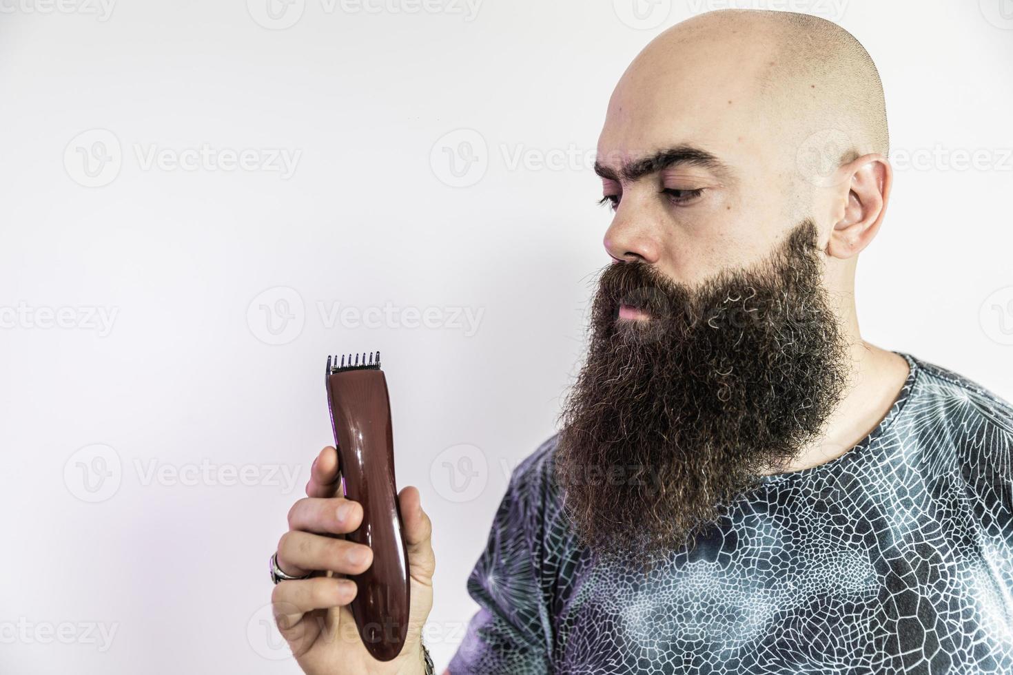 bebaarde man scheert zijn baard met een elektronisch scheerapparaat foto