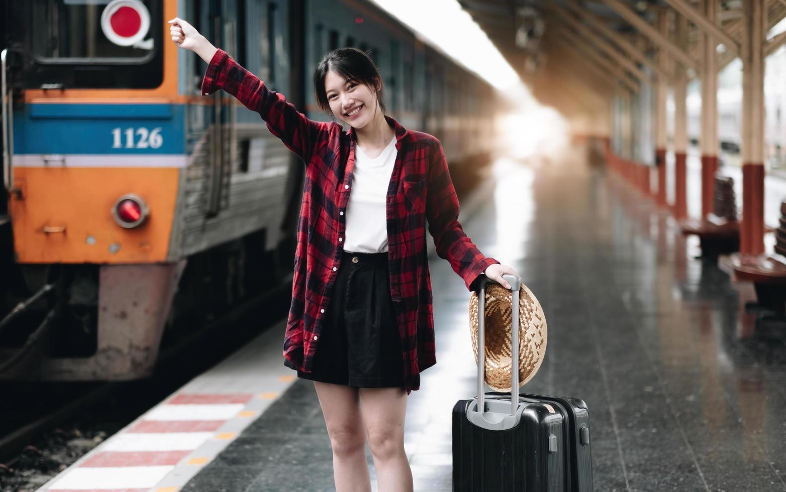 jonge reizigersvrouw op zoek naar een vriend die een reis plant op het treinstation. zomer en reizen lifestyle concept foto